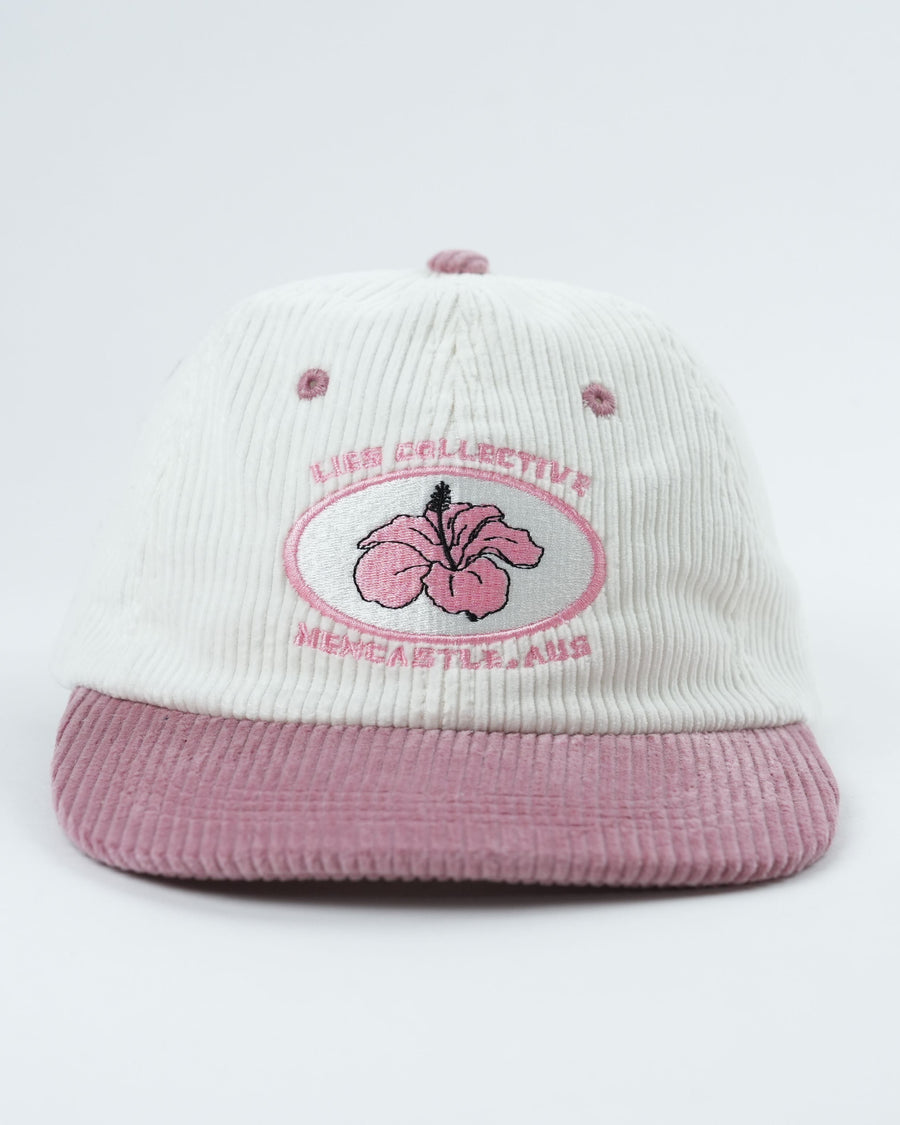 White corduroy cap with mauve brim and large embroidered flower logo on front.