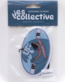Oval blue lies collective air freshener with strawberry scent label in package.